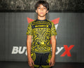 Child wearing a black and yellow patterned shirt with 'Butterfly' branding in front of a branded backdrop.